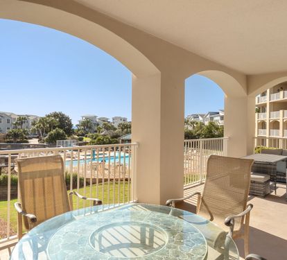 Spacious covered balcony with pool views and comfortable seating for dining and lounging.