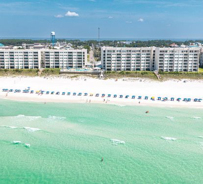 A stunning beachfront property on pristine white sand, with crystal-clear turquoise waters stretching along the Gulf Coast, surrounded by a peaceful coastal community.
