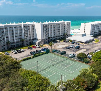 Beachfront property featuring tennis courts, pool, and direct access to pristine white sand beaches along the emerald coast.