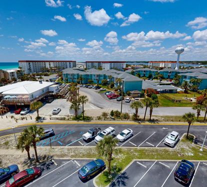 Aerial view showcasing the beachfront property location with convenient parking, nearby coastal lodging, and a water tower marking the surrounding neighborhood.