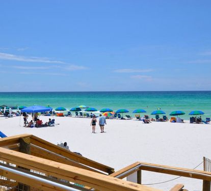 Spacious private beach with sugar-white sand, colorful umbrellas, and emerald Gulf waters—ideal for relaxing, swimming, and soaking up the laid-back coastal atmosphere.