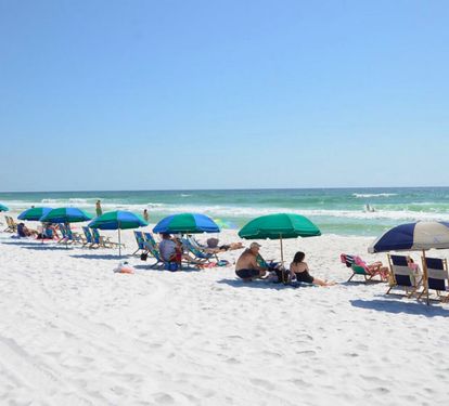 Sun-soaked private beach with sugar-white sand, emerald Gulf waters, and colorful umbrellas creating the perfect setting for relaxing, swimming, and enjoying classic Emerald Coast beach days.