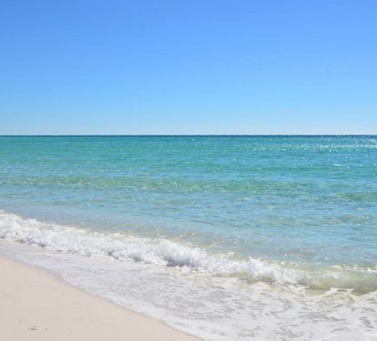 Clear emerald Gulf waters gently meeting sugar-white sand, creating a serene coastal shoreline perfect for swimming, beach walks, and soaking up the relaxed Emerald Coast atmosphere.