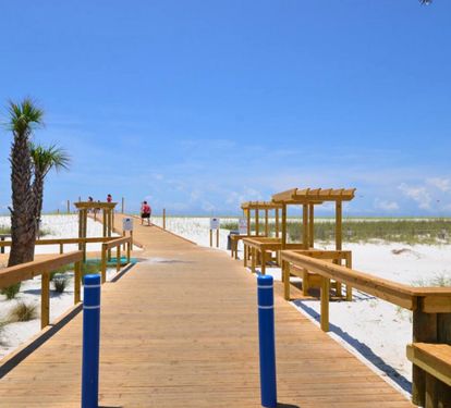 Wooden boardwalk leading to a private, sugar-white sand beach with shaded pavilions and sweeping Gulf views—an inviting path to relaxing beach days and unforgettable Emerald Coast sunsets.