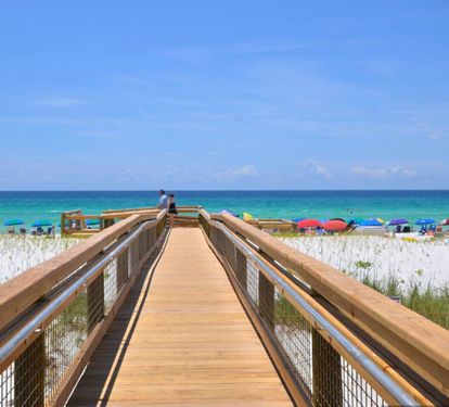 Scenic boardwalk at Sandpiper Cove Resort leading to a private, sugar-white sand beach with sweeping views of emerald Gulf waters and a relaxed, coastal atmosphere.