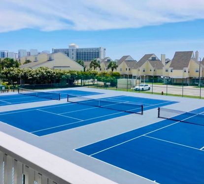 Lighted tennis courts at Sandpiper Cove Resort, offering a pristine setting for casual matches or competitive play, surrounded by lush landscaping and a relaxed coastal resort atmosphere.