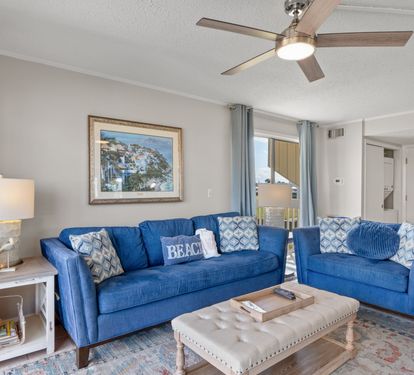 Relax in this bright coastal living space featuring comfortable seating, stylish beach-inspired décor, and easy access to the private patio overlooking the golf course. A perfect spot to unwind after a day in the sun.