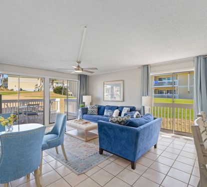 This bright and open coastal living area offers comfortable seating, abundant natural light, and peaceful golf course views just outside. The open layout creates the perfect space for relaxing, gathering, and enjoying a laid-back beach getaway.