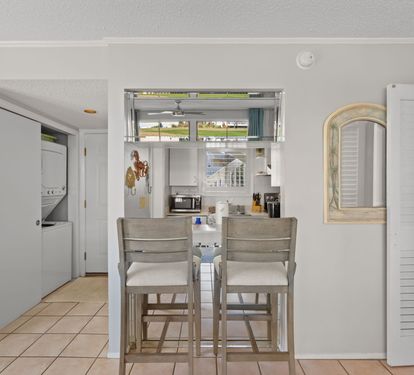 The breakfast bar offers additional seating for casual meals, snacks, or evening drinks, with an open pass-through design connecting the kitchen and living area for an easy, relaxed coastal feel.