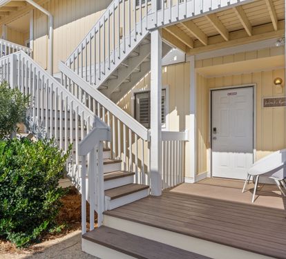 A welcoming coastal-style entrance awaits at unit 1060, featuring a shaded front deck with seating.