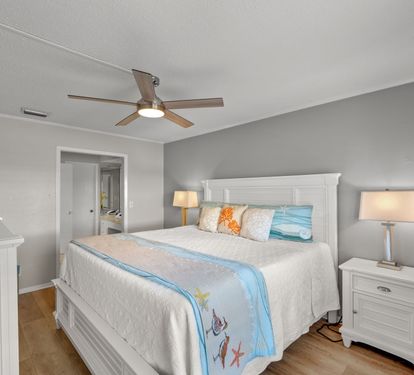The primary bedroom offers a comfortable king bed, coastal-inspired décor, and a peaceful atmosphere perfect for relaxing after a day at the beach. A bright and inviting retreat designed for comfort and rest.