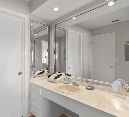 The dressing area features a spacious vanity with ample counter space, bright lighting, and large mirrors, creating the perfect spot to get ready for a day at the beach or an evening out.