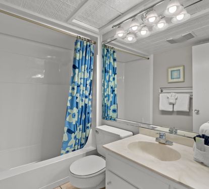 Your private bathroom features bright lighting, a tub-shower combo, and cheerful touches to refresh after beach adventures.