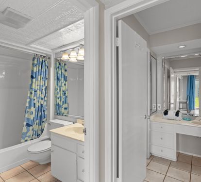 Bright and spacious bathroom with a tub/shower combo and cheerful blue-accented decor, plus a separate vanity area for your morning routine.
