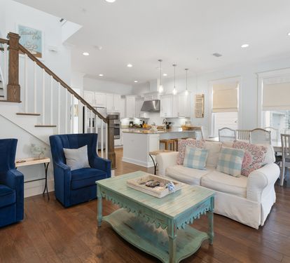 Settle into your coastal-inspired open living space where navy chairs and mint accents create perfect harmony for relaxing after beach days.