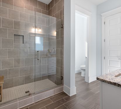 Step into your spa-like sanctuary with a gorgeous walk-in shower featuring elegant gray tiles and warm lighting for ultimate relaxation.