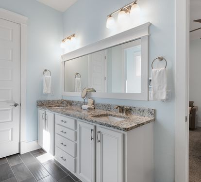 Your elegant bathroom features double vanities with granite countertops and soft blue walls for a serene morning routine.