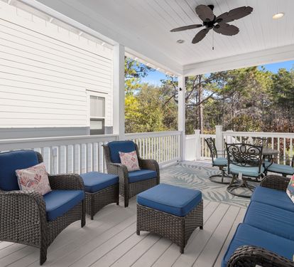 Unwind on your private covered porch with comfortable seating and ceiling fan, overlooking peaceful wooded surroundings.