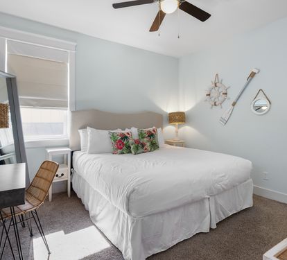 Unwind in your serene bedroom featuring crisp white linens, tropical accents, and coastal charm that invites peaceful rest.