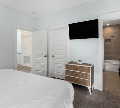 Your master bedroom features a cozy bed, wall-mounted TV, and stylish dresser, with an ensuite bathroom for ultimate comfort.