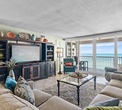 Sink into plush sofas while ocean waves dance beyond your floor-to-ceiling windows in this elegant beachfront living room.