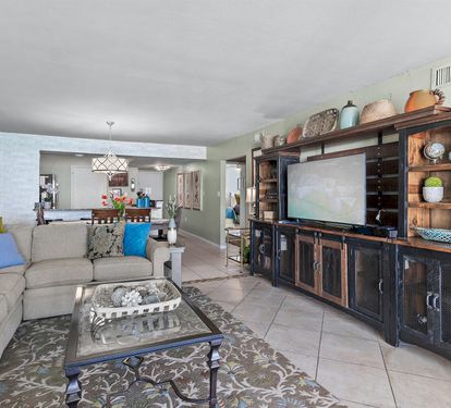Relax in your spacious living area with plush sectional seating, entertainment center, and open layout flowing to the modern kitchen.
