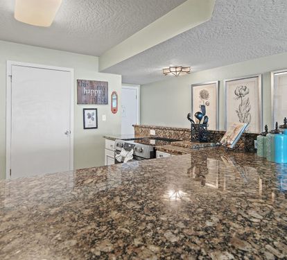 You'll love cooking in this spacious kitchen with gleaming granite counters, modern appliances, and charming botanical artwork creating a welcoming culinary haven.