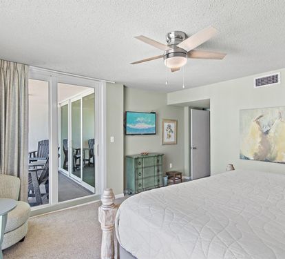 Drift off in your serene bedroom with coastal artwork and gentle ceiling fan, while French doors reveal your private balcony retreat.