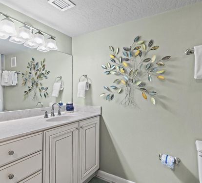 Your private spa-like bathroom features elegant vanity, decorative tree art, and fluffy towels for ultimate relaxation.