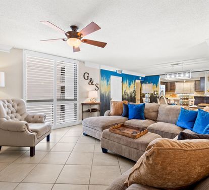 Unwind in your spacious living room featuring plush seating and vibrant coastal artwork that brings beachside tranquility indoors.