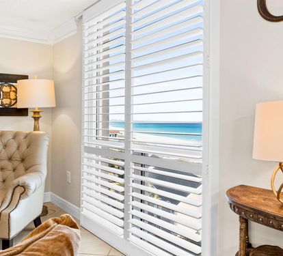 Sink into your private seating area where ocean breezes drift through elegant blinds, framing stunning sea views.