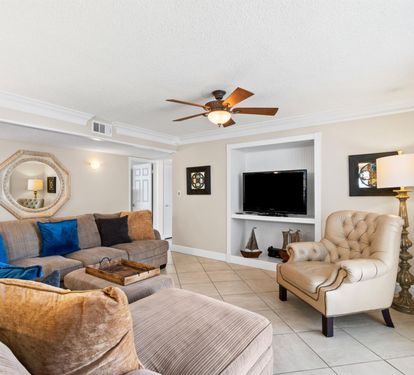 Unwind in your spacious living room with plush sectional seating, entertainment center, and coastal decor creating the perfect retreat atmosphere.