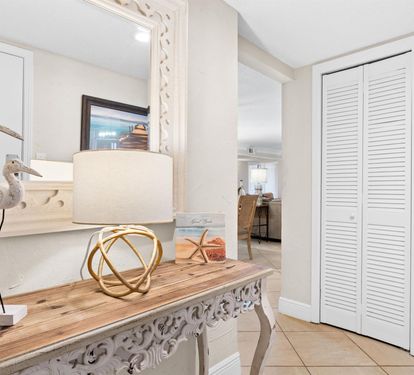 Your elegant entryway welcomes you with coastal charm and thoughtful storage behind beautifully crafted white louvered closets.