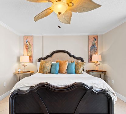 Unwind in this elegant bedroom featuring a plush bed with tropical-inspired linens and charming peacock artwork that sets a serene tone.