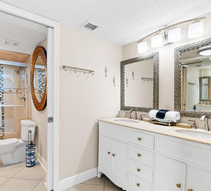 Your spacious bathroom features dual vanities, elegant mirrors, and a stunning mosaic tile shower—perfect for refreshing after beach adventures.