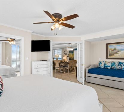 Relax in your spacious bedroom featuring ocean artwork, a cozy daybed, and ceiling fan for your comfort.