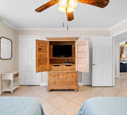 Relax in your charming bedroom featuring rustic wood furniture, a ceiling fan for comfort, and thoughtful storage in the beautiful armoire.