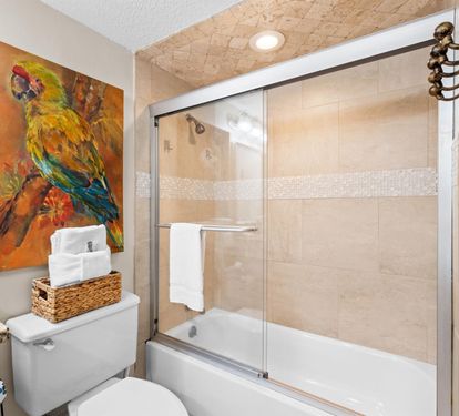 Refresh in your private spa-like bathroom featuring elegant tile work, tropical artwork, and thoughtful amenities.