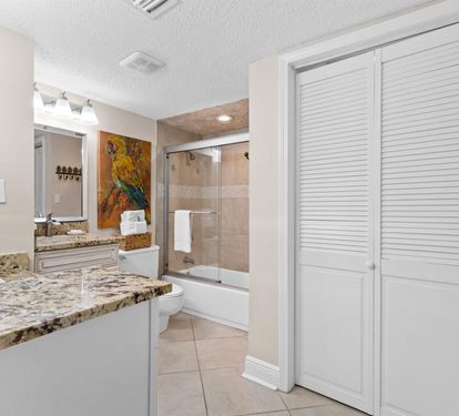 Unwind in your elegant bathroom with granite counters, glass shower, and tropical artwork adding coastal charm.