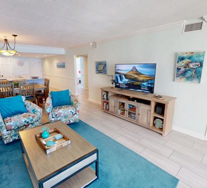 Relax in your bright, coastal-themed living space where ocean artwork and turquoise accents create the perfect beach vibe for your getaway.