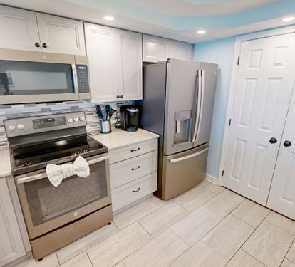 Your fully equipped kitchen features pristine white cabinets, stainless steel appliances, and a stylish tile backsplash—perfect for whipping up delicious meals during your stay.