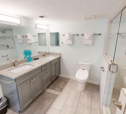 Refresh in your spacious bathroom featuring dual vanities, modern glass shower, and pristine finishes for ultimate comfort.