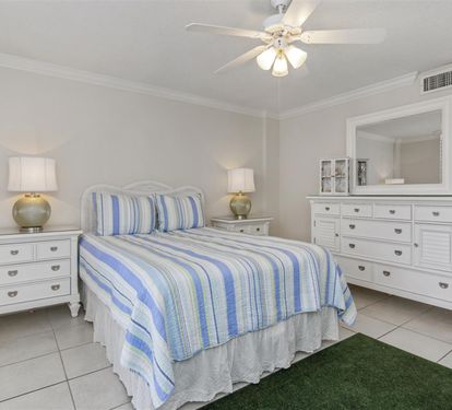 Your bright bedroom features coastal-striped linens and crisp white furniture, creating a serene retreat with thoughtful touches.