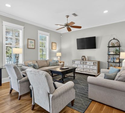 Relax in your spacious living room with comfortable seating, modern entertainment, and abundant natural light streaming through tall windows.