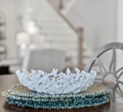 Admire elegant touches like this delicate coral bowl centerpiece while you dine at your stylish glass table.