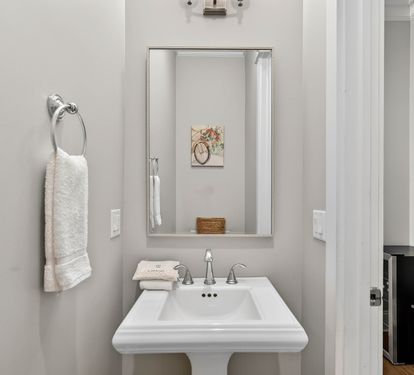 Refresh in your stylish powder room with coastal charm, featuring crisp white fixtures and thoughtful beach-themed touches.