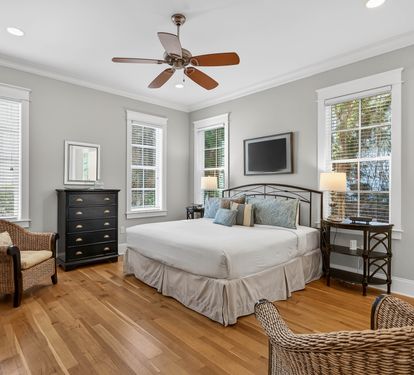 Relax in your serene bedroom featuring elegant hardwood floors, natural light from multiple windows, and a ceiling fan to keep you comfortable year-round.