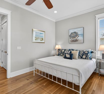 Relax in your peaceful bedroom with coastal charm, where warm wood floors and beach-inspired art create the perfect retreat.