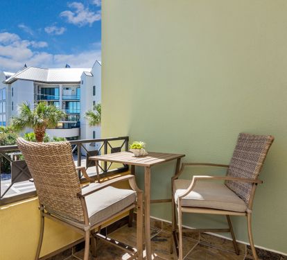 Cozy private balcony with bistro seating and palm-lined views—perfect for morning coffee or evening drinks on 30A.