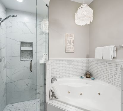 Relax and unwind in the spa-inspired primary bath featuring a jetted soaking tub, walk-in glass shower, and elegant coastal finishes.